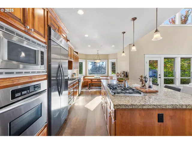 a kitchen view with stainless steel appliances granite countertop a stove and a wooden cabinets