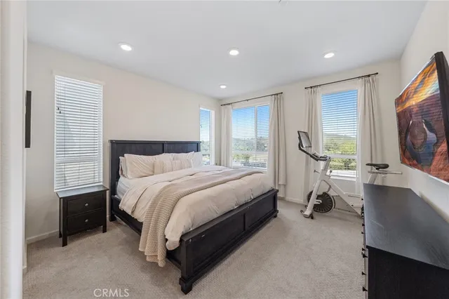 a spacious bedroom with a bed and a flat screen tv