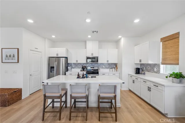 a kitchen with stainless steel appliances kitchen island granite countertop a dining table chairs and sink