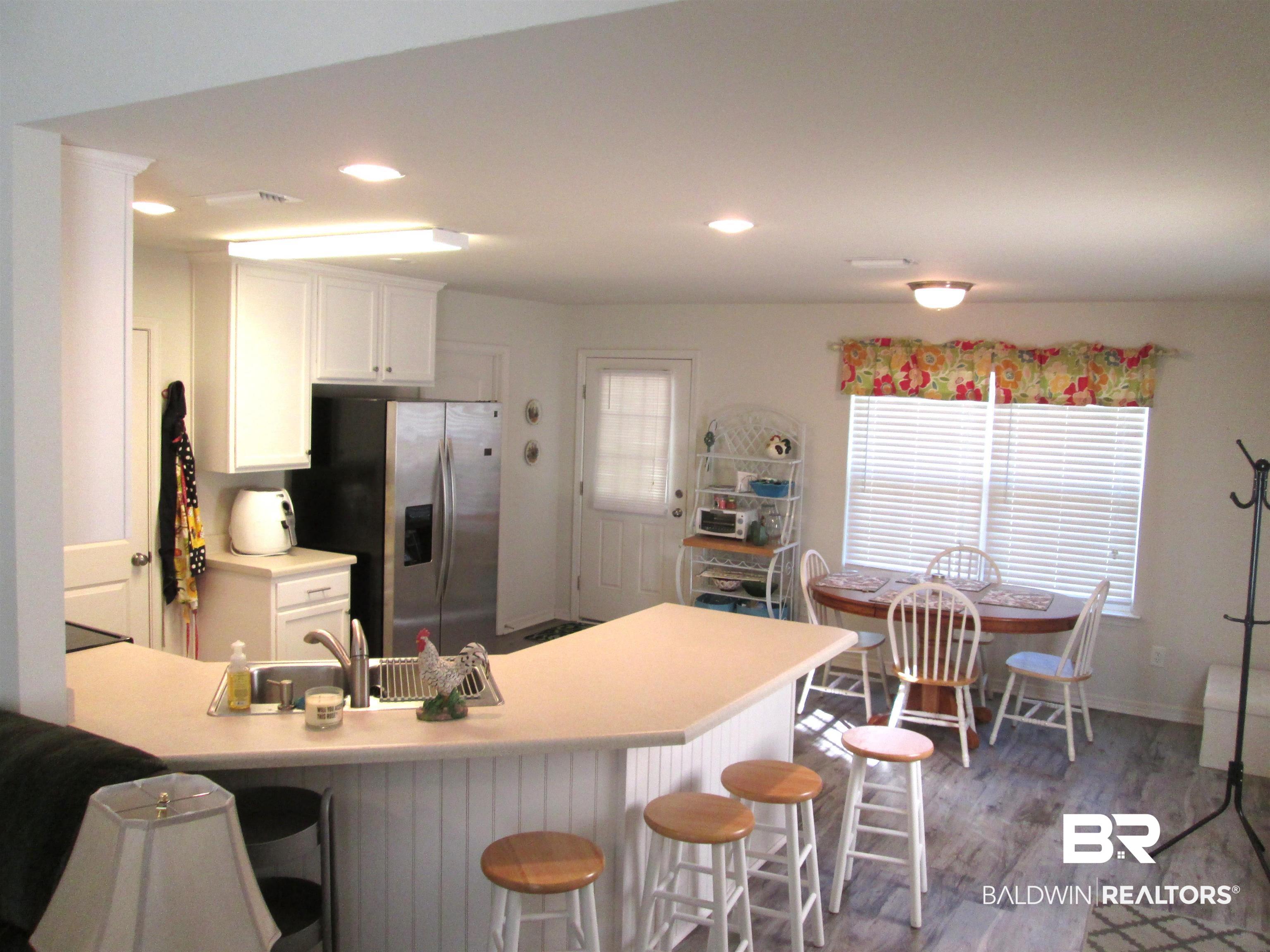 530 Brethren Church Road Fruitdale, AL 36539 - Photo 7 of 24 Kitchen with kitchen peninsula, white cabinetry, light hardwood / wood-style floors, stainless steel fridge with ice dispenser, and a breakfast bar area