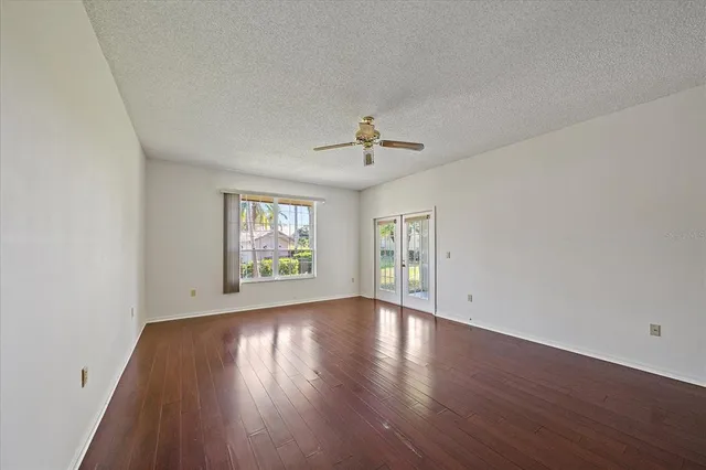 an empty room with wooden floor and windows
