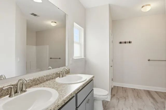 a bathroom with a granite countertop sink a toilet and a mirror