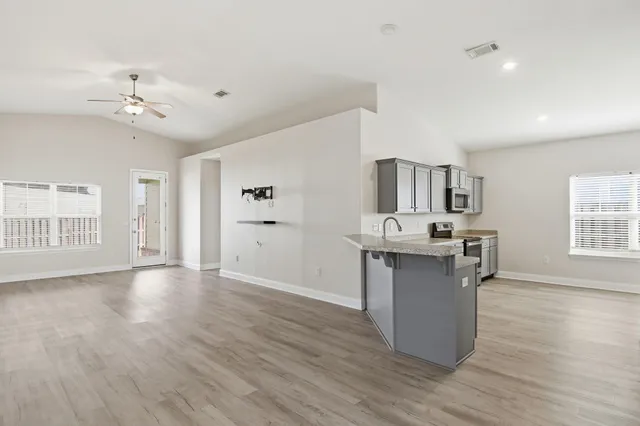 a view of an empty room with a kitchen and wooden floor