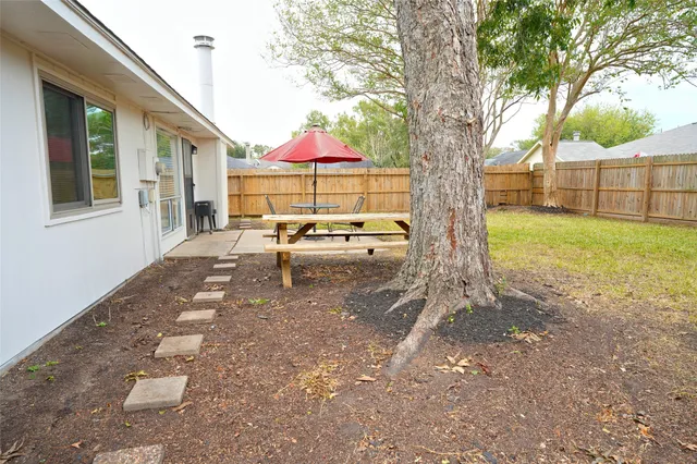 a view of backyard with a table and chairs under an umbrella