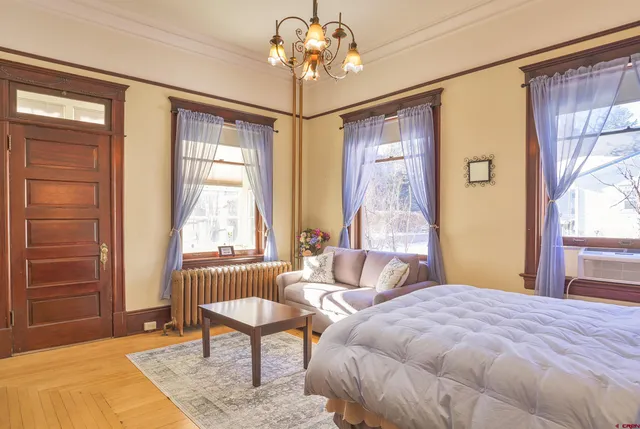 a bedroom with a bed a couch and a potted plant on the dresser