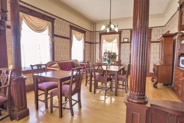 a view of a dining room with furniture a chandelier and large windows