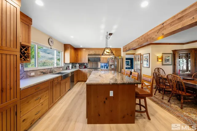 a view of a kitchen with kitchen island granite countertop a large window and stainless steel appliances