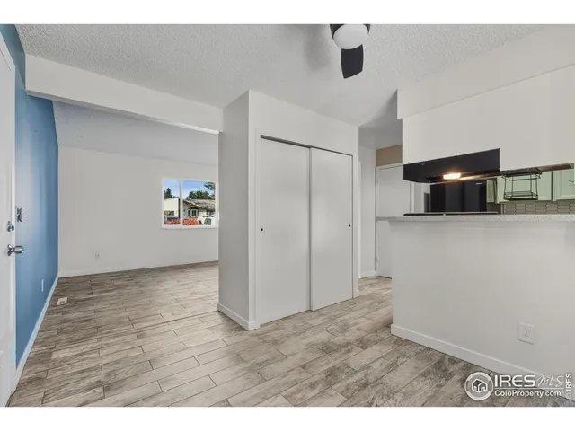 a view of a refrigerator in kitchen and an empty room