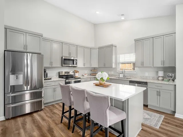a kitchen with stainless steel appliances granite countertop a stove a refrigerator a sink a dining table and chairs