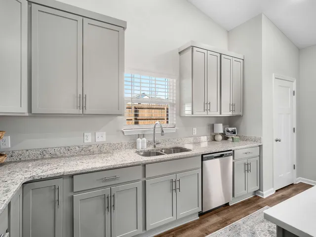 a kitchen with stainless steel appliances granite countertop white cabinets sink and window