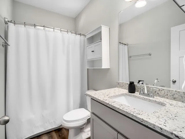 a bathroom with a granite countertop sink toilet and a mirror