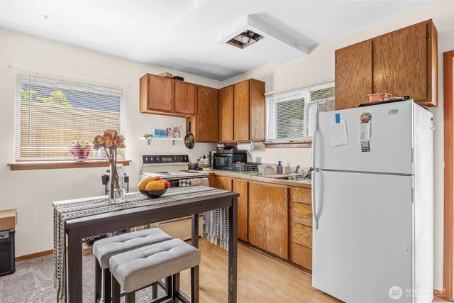 a kitchen with stainless steel appliances a refrigerator a sink a stove a table and chairs