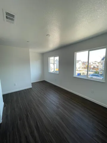 a view of an empty room with wooden floor and a window