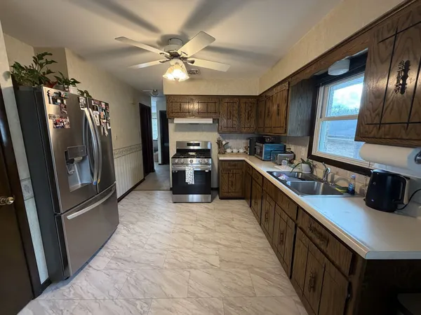 a large kitchen with stainless steel appliances sink a stove and cabinets