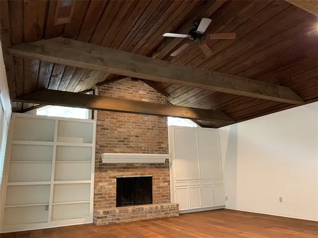 a view of an empty room with wooden floor and a fireplace