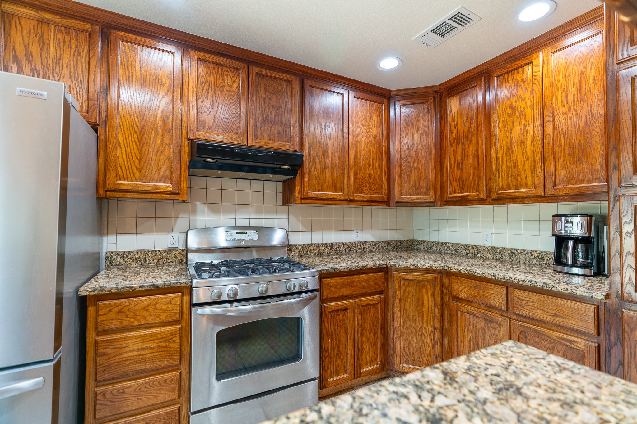 400 619th Spur Elgin, TX 78621 - Photo 25 of 40 Rich wood cabinetry and speckled granite counters create a warm, inviting atmosphere in this functional kitchen.