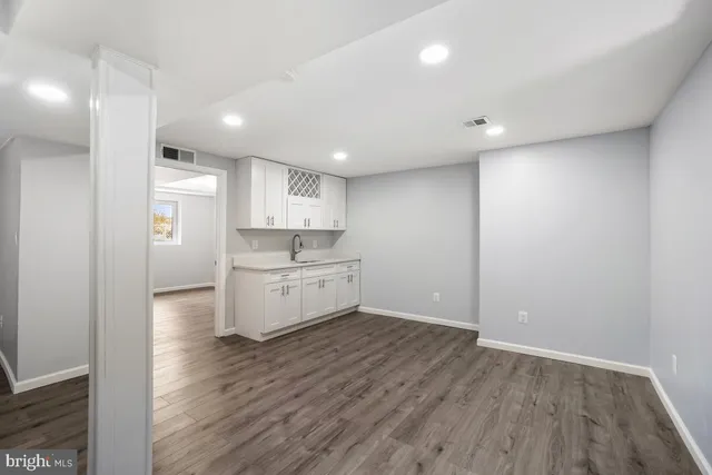 a view of a kitchen with white cabinets and wooden floor