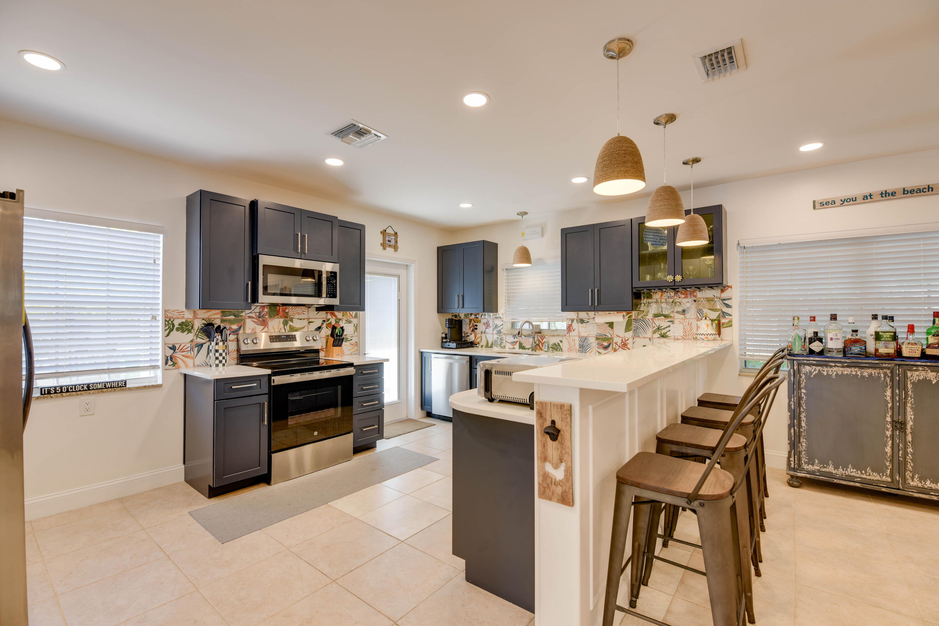 1720 Patricia Street Key West, FL 33040 - Photo 42 of 46 a kitchen with stainless steel appliances kitchen island granite countertop a stove top oven a sink dishwasher a dining table and chairs with wooden floor