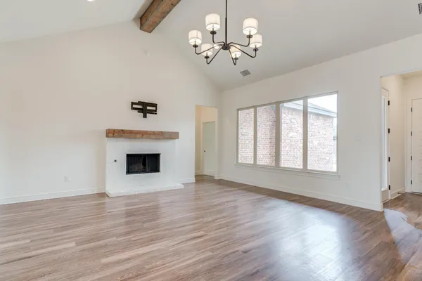 a view of a livingroom with a fireplace wooden floor and windows