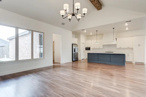a view of an empty room with kitchen and window