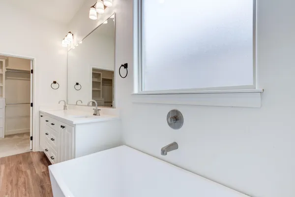 a spacious bathroom with a double vanity sink a mirror and a bathtub