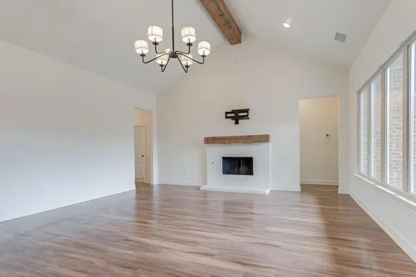 a view of a livingroom with a fireplace a chandelier and wooden floor