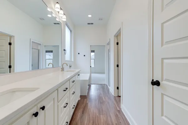 a spacious bathroom with a double vanity sink a mirror and a shower