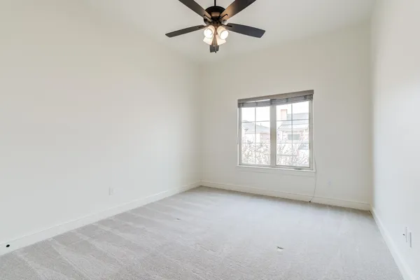 an empty room with a window and a fan