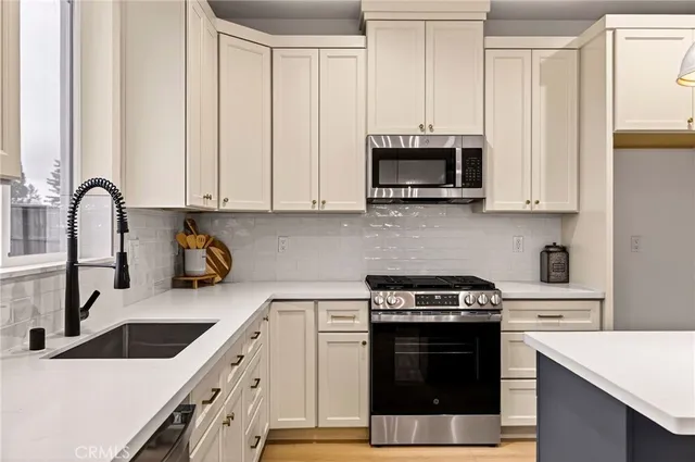 a kitchen with stainless steel appliances granite countertop a stove a sink and a microwave