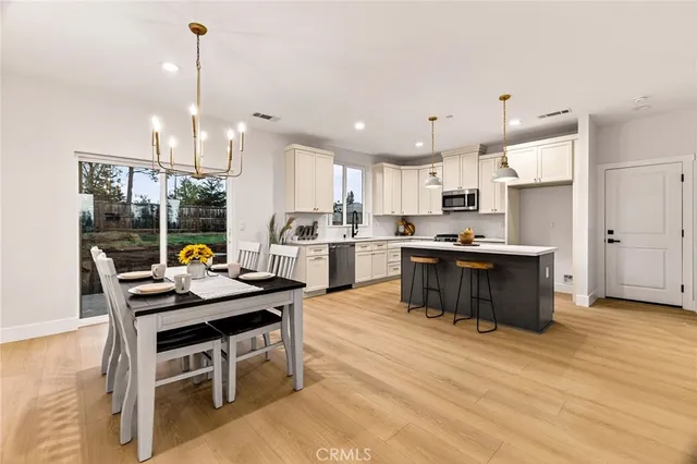 a kitchen with stainless steel appliances kitchen island granite countertop a table chairs and a stove