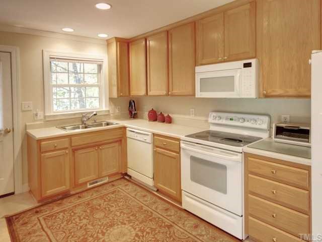 6625 Coach Light Circle Raleigh, NC 27613 - Photo 4 of 12 Kitchen with tile floors, custom cabinetry, smooth top stove, built in microwave. Kitchen has an eat in area and leads to the deck.