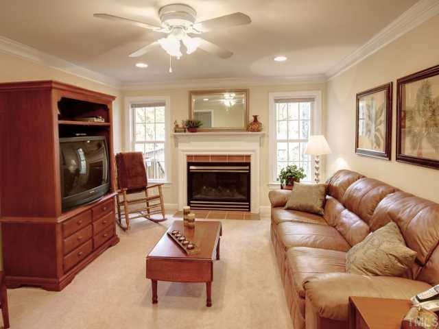 6625 Coach Light Circle Raleigh, NC 27613 - Photo 5 of 12 Family room with recessed lighting, ceiling fan, fireplace with tile surround, and 2 piece crown.