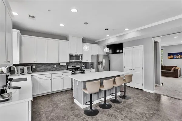 a kitchen with stainless steel appliances a sink a stove a refrigerator cabinets and a dining table