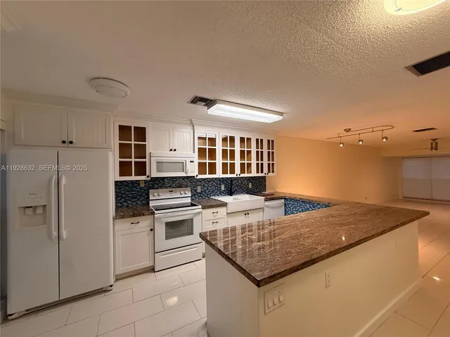 a kitchen with kitchen island granite countertop a stove and a refrigerator