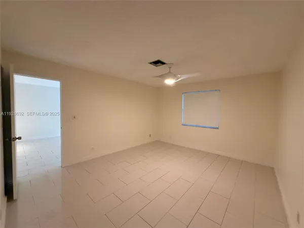 an empty room with chandelier fan and windows