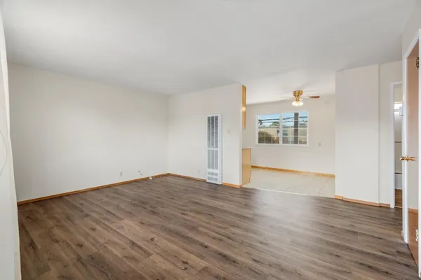 a view of an empty room with wooden floor and a window