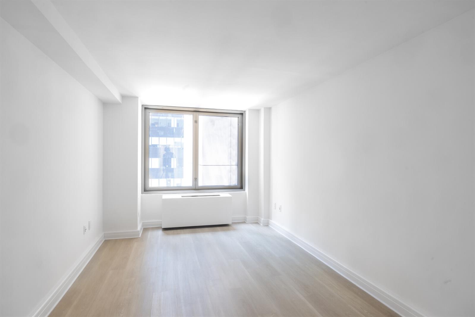 101 West 55th Street, Unit 701 Manhattan, NY 10019 - Photo 3 of 11 an empty room with wooden floor and windows