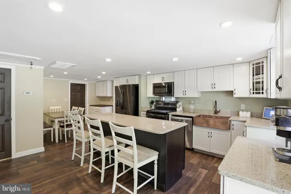 a kitchen with stainless steel appliances kitchen island granite countertop a sink a stove a dining table and chairs