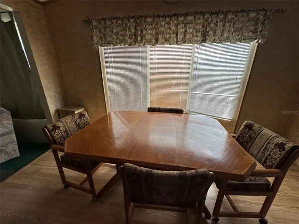 a kitchen with stainless steel appliances wooden floors sink refrigerator dining table and chairs