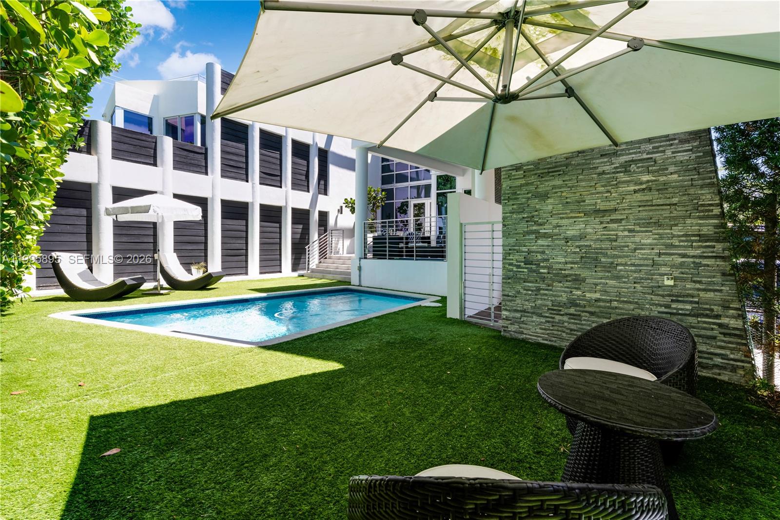 548 Fernwood Road, Unit 548 Key Biscayne, FL 33149 - Photo 36 of 50 a view of pool with lawn chairs and large trees
