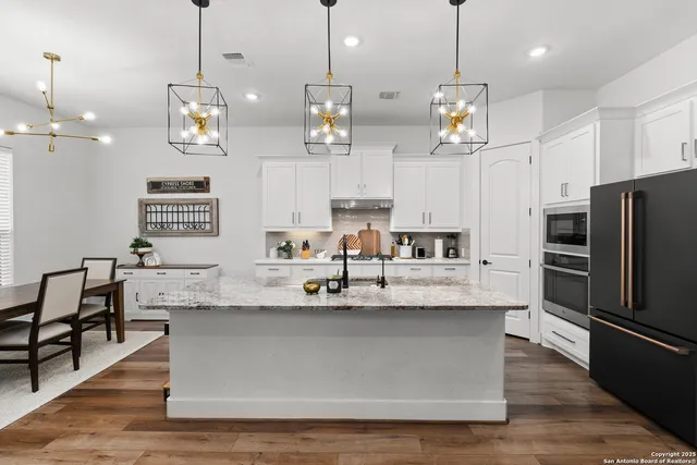 a large kitchen with kitchen island stainless steel appliances a large center island and a wooden floor