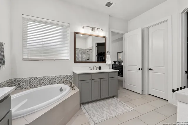 a bathroom with a tub a sink and mirror