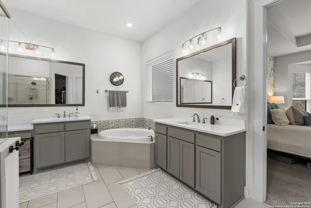 a spacious bathroom with a double vanity sink mirror and bathtub