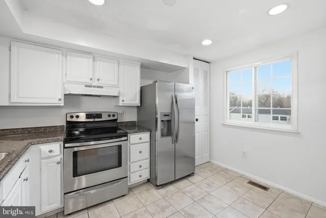 a kitchen with cabinets stainless steel appliances and a window