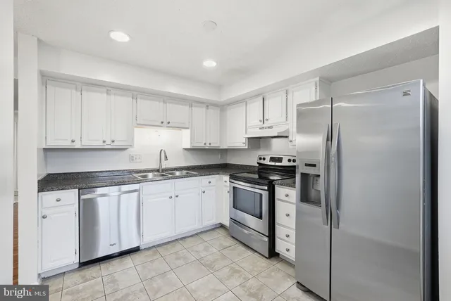a kitchen with granite countertop white cabinets and stainless steel appliances