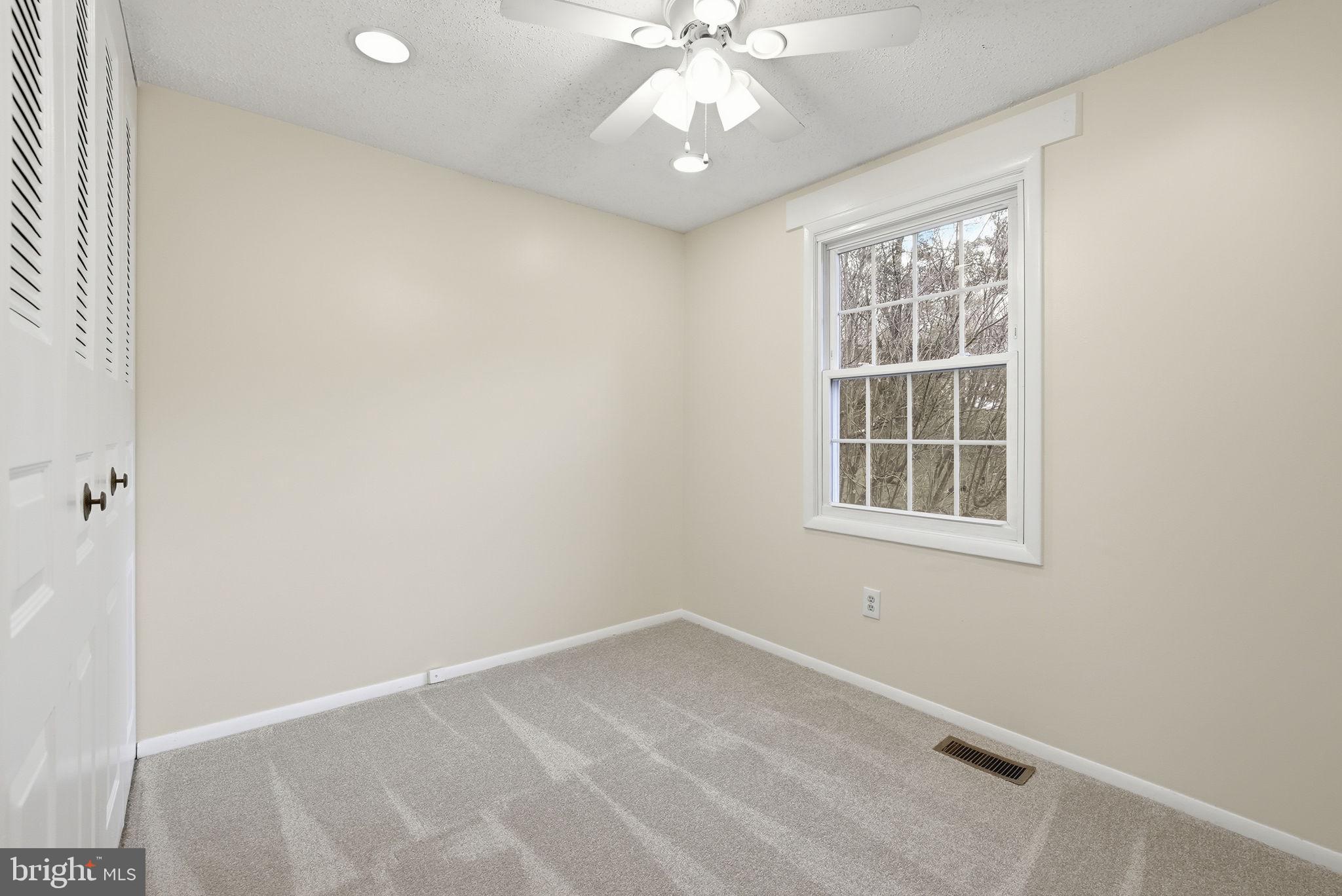 9804 Gabon Court Burke, VA 22015 - Photo 20 of 30 an empty room with a chandelier fan and windows