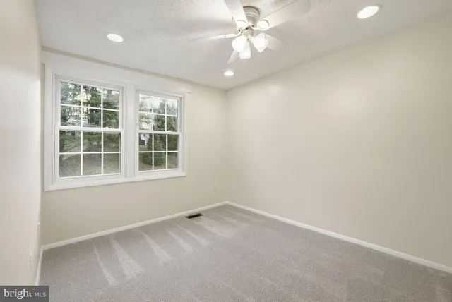 an empty room with a window and a fan