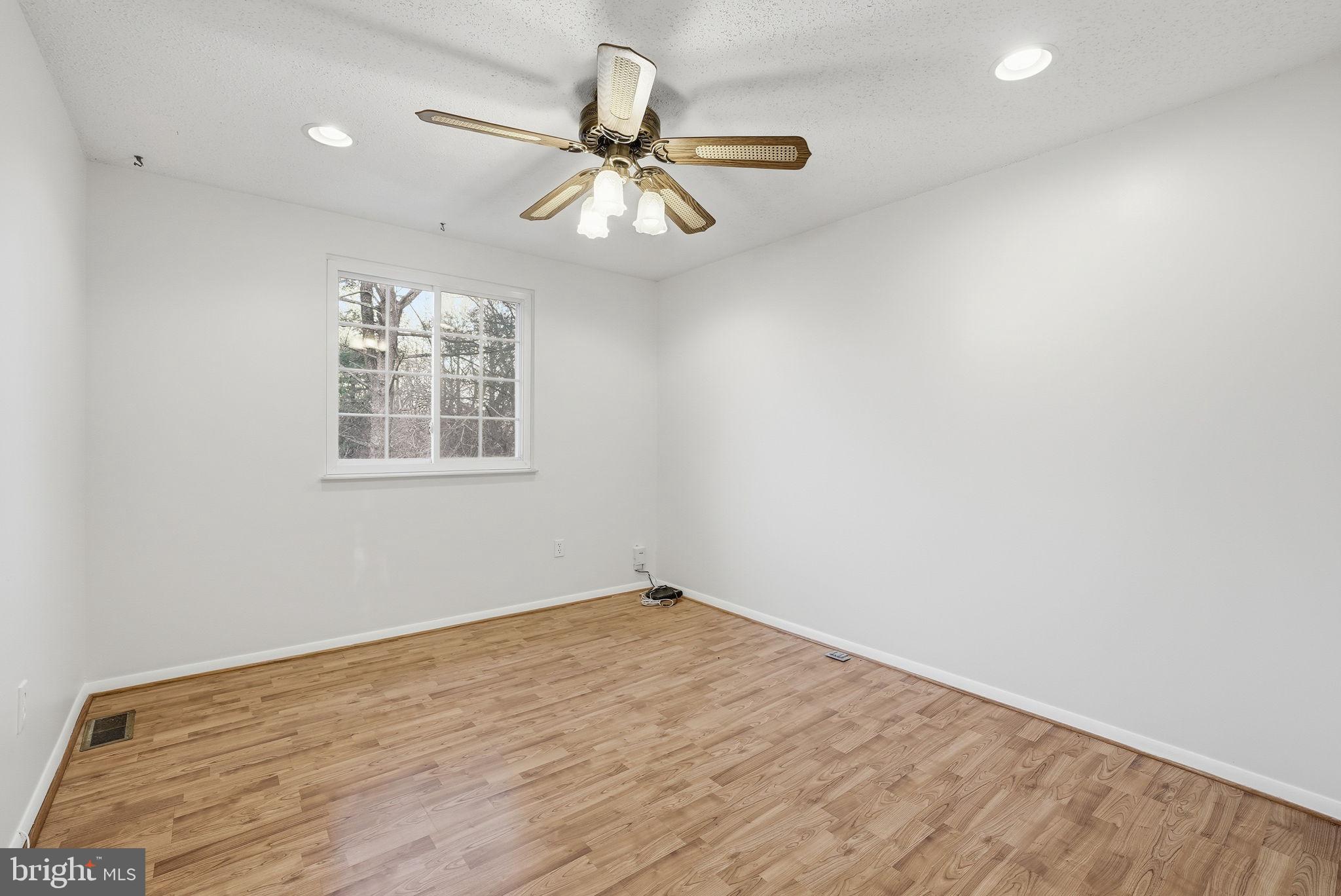 9804 Gabon Court Burke, VA 22015 - Photo 9 of 30 an empty room with wooden floor fan and windows