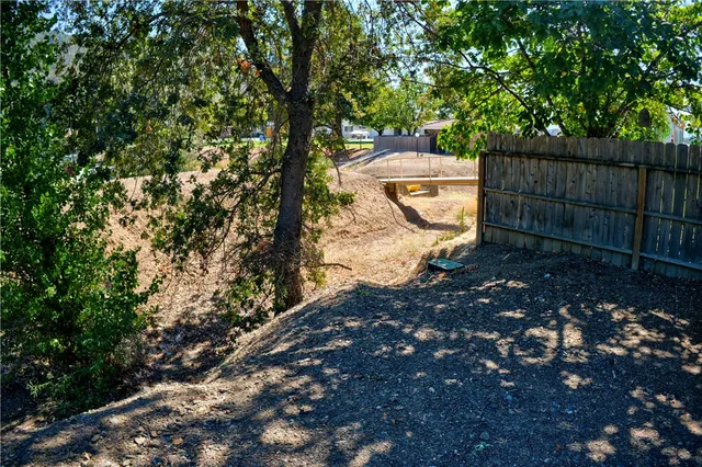 a view of a backyard with wooden fence and a tree