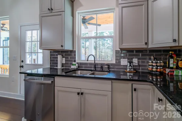 a kitchen with stainless steel appliances granite countertop a sink a window and cabinets
